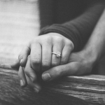 a couple holding hands with a wedding ring visible